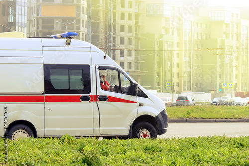 Emergency medical vehicle navigating through urban landscape under bright sunlight