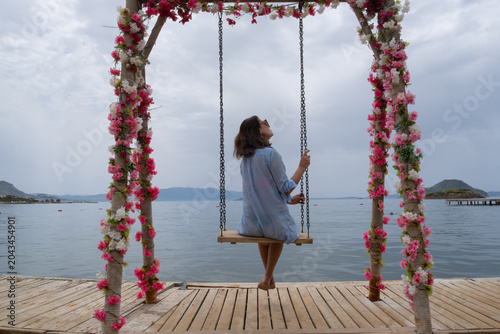 Swinging by the sea at a resort during cloudy weather with a person enjoying the view from the dock