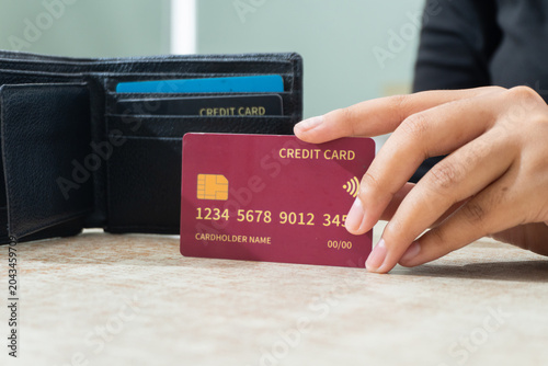 Tableau sur toile Hand holding a contactless credit card next to a wallet