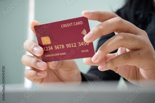 Close-up of hands holding a contactless credit card for digital payment. Concept of cashless transactions, online shopping, banking, financial technology, and secure electronic payments.