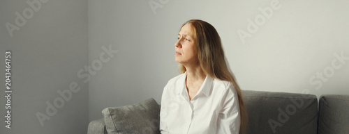 Pensive woman thinks looks out the window, thoughtful girl suffering from depression at home