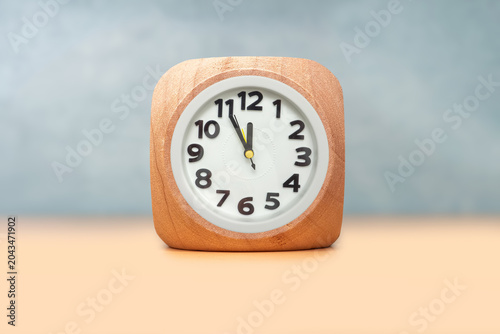 Wooden cube with clock showing five minutes to twelve symbolizing last chance and urgent deadline