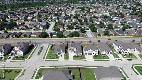 Main road corridor through Arlington, TX frames rows of homes, parked cars neatly kept lawns extending across dense suburban grid. Long sightlines along central roadway highlight traffic flow