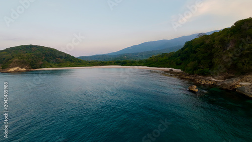 Bilde på lerret Aerial view of a secluded tropical bay framed by forested hills and clear blue water
