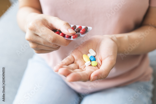 Fotografie Sick ill asian young woman, girl hand taking tablet pill capsule out from blister pack, painkiller medicine from stomach pain, head ache, pain for treatment, take drug or vitamin at home, health care