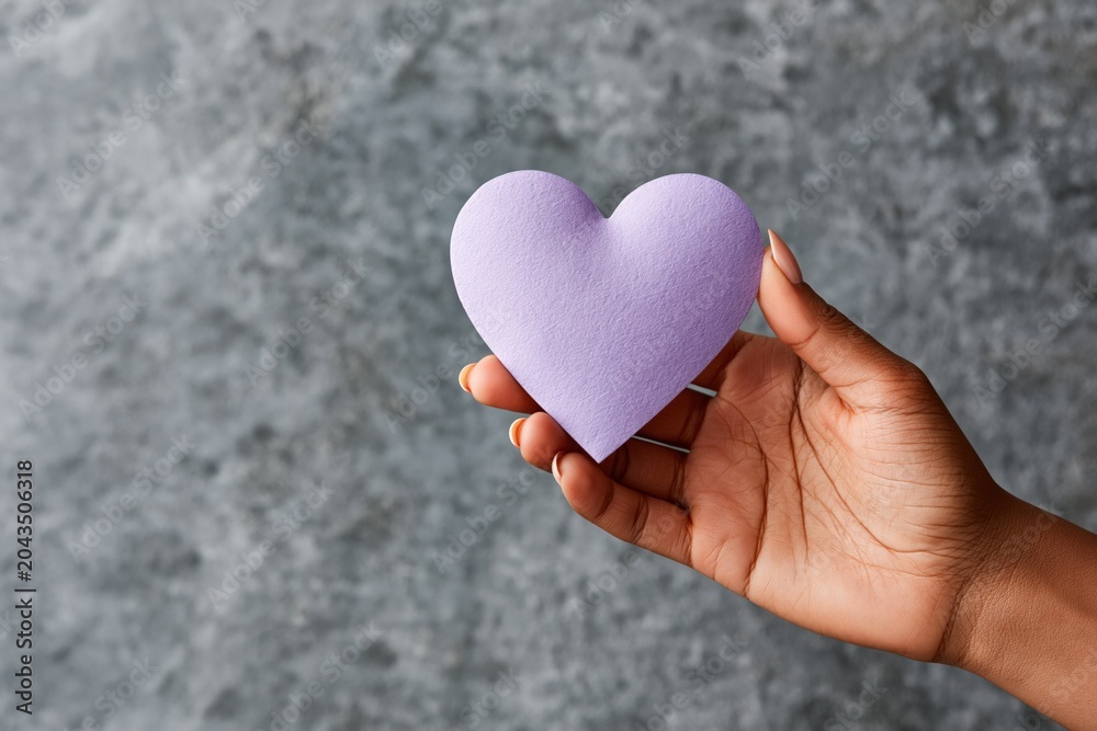 Fototapeta premium Closeup of hand holding lavender paper heart for greeting card background and romantic banner design