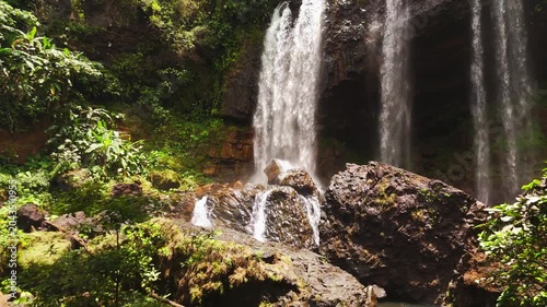 Vertical format aerial drone footage of Tad Tayicseua Waterfall, Attapeu Province, southern Laos. The portrait orientation captures the full height of the waterfall dropping through dense tropical jun