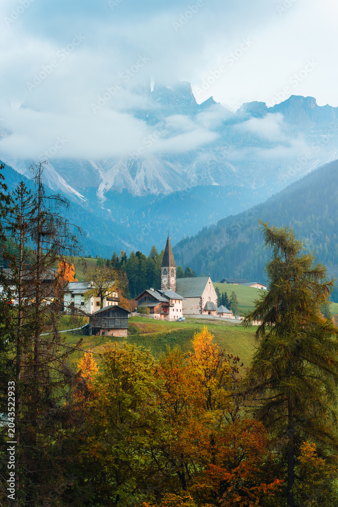 Obraz premium Scenic Alpine Village with Stone Church of St Magdalena and Dolomites Mountain in Autumn Season Italy
