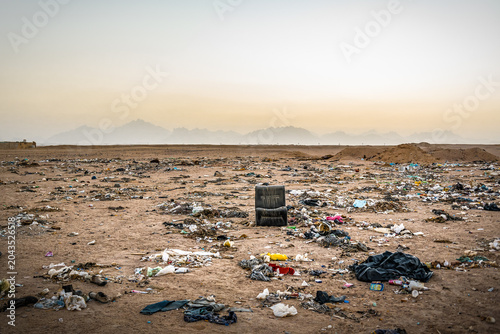 Massive illegal garbage dump in the middle of a desert landscape with mountains on the horizon.