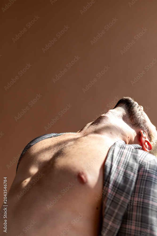 Naklejka premium Low-angle close-up of a shirtless white man in dramatic light