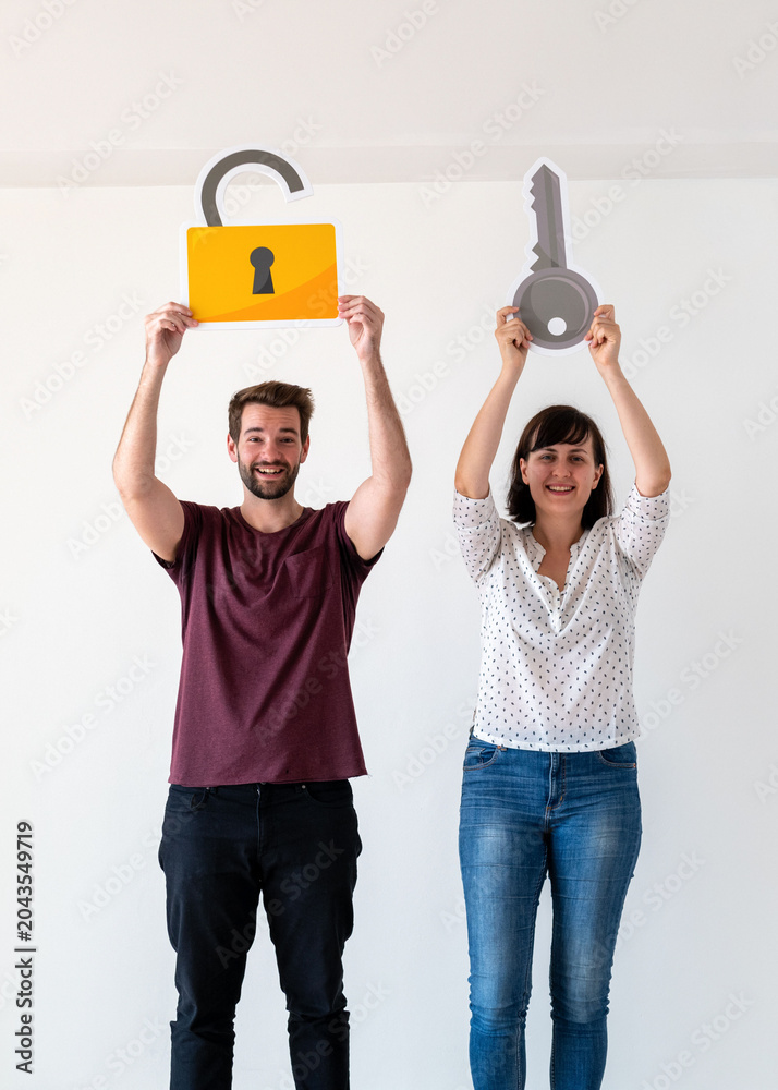 Obraz premium Two people holding a lock and key cutout, smiling in a bright room.