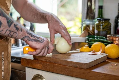 Canvastavla Tattooed chef slicing onion precisely.