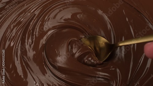 Melted chocolate scooping with a spoon, close up. Smooth glossy texture and dessert preparation process