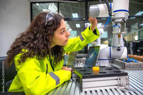 Professional female robotic engineer doing research on artificial intelligent robot software update for industrial machinery in modern R and D facility
