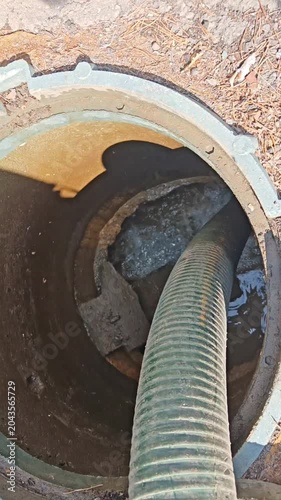  Septic tank. Pipe in a drainage pit. Pumping wastewater from a septic tank. Septic tank maintenance. Sewage pumping machine. Vertical

 