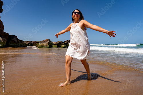 Beautiful middle-aged woman enjoying walk on beach on sunny summer day
