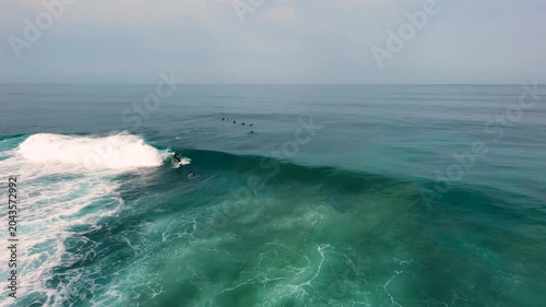 Aerial drone view of surfers, surfing paddling, duck diving, with beautiful blue collars and glass sea