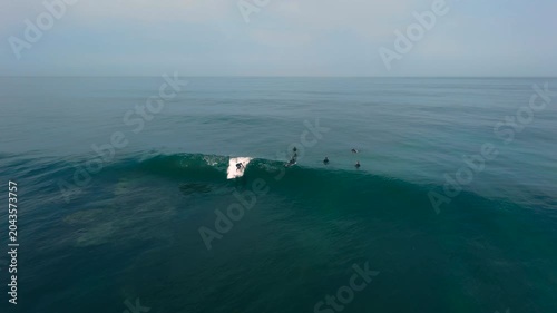 Aerial drone view of surfers, surfing paddling, duck diving, with beautiful blue collars and glass sea