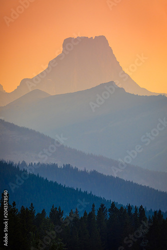 Mountain peaks silhouetted by vibrant orange sunset sky