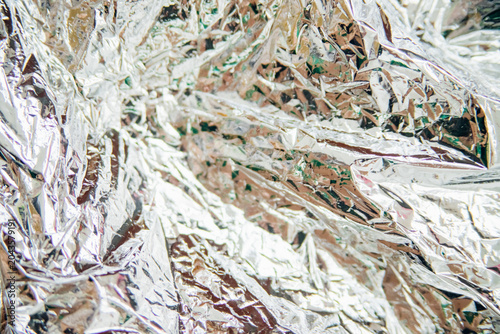 Crumpled silver foil. The background shimmers with all the colors of the rainbow.