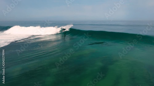 Aerial drone view of surfers, surfing paddling, duck diving, with beautiful blue collars and glass sea