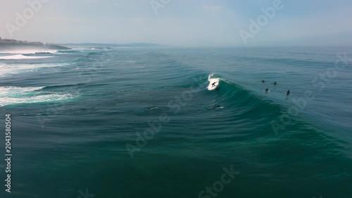 Aerial drone view of surfers, surfing paddling, duck diving, with beautiful blue collars and glass sea