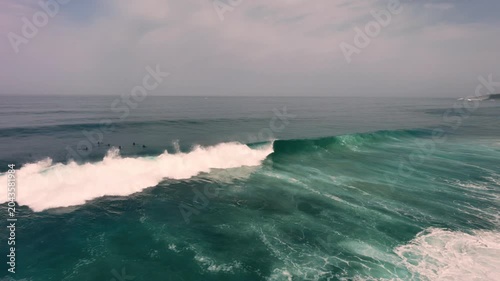 Aerial drone view of surfers, surfing paddling, duck diving, with beautiful blue collars and glass sea