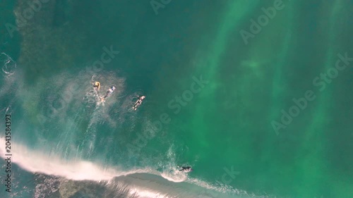 Aerial drone view of surfers, surfing paddling, duck diving, with beautiful blue collars and glass sea