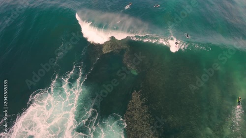 Aerial drone view of surfers, surfing paddling, duck diving, with beautiful blue collars and glass sea
