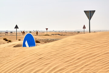 Roundabout road traffic circle signs buried under desert sand dune