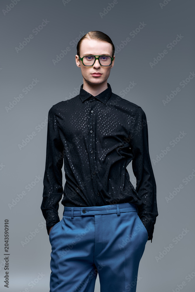 Fototapeta premium Young man showcases modern fashion with confidence in stylish studio portrait