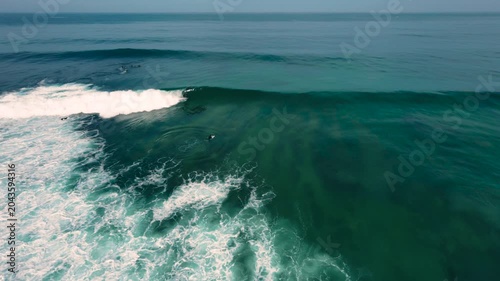 Aerial drone view of surfers, surfing paddling, duck diving, with beautiful blue collars and glass sea