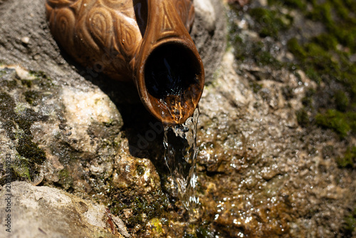 A waterfall in the forest flows from a jug.