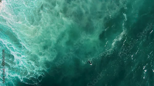 Aerial drone view of surfers, surfing paddling, duck diving, with beautiful blue collars and glass sea