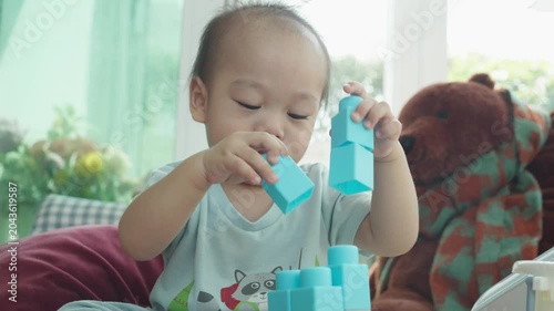 A young child engages in creative play with colorful building blocks in a comfortable setting. The soft lighting and cozy background create a nurturing atmosphere for learning and development.