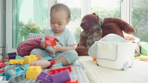A young child interacts with vibrant toys in a cozy playroom setting, surrounded by a plush bear and colorful blocks. The scene captures a joyful moment of exploration and creativity.