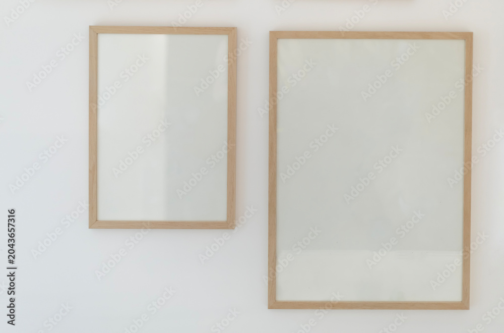 Fototapeta premium Two blank wooden poster frames hanging on white wall mockup template