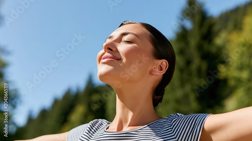 Young woman in the mountains with arms open enjoying the fresh air and nature