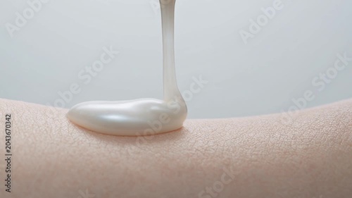 Macro Close-up of pearlescent cosmetic product being applied to smooth human skin, illustrating hydration, beauty, and skincare routine.