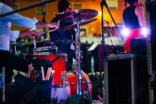 Obraz na plátně Drummer playing drums during a live music concert with musicians on stage