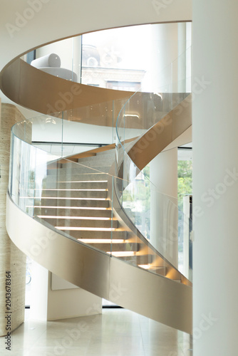 Spiral staircase with illuminated steps and glass railing in modern interior