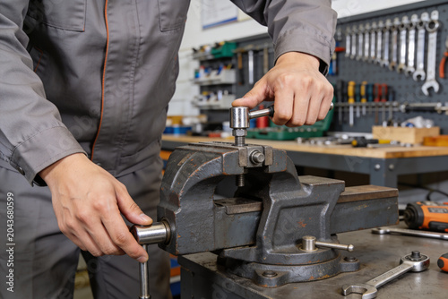 Foto Mechanic using a wrench to tighten a bolt in a vise at a workbench