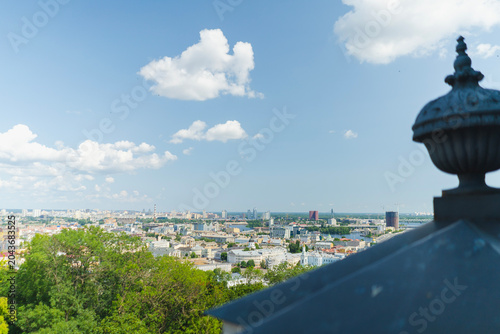 The Ukrainian national flag flutters above the city skyline as a symbol of independence. Buildings and landmarks in the historic city center, including a Ferris wheel and streets.