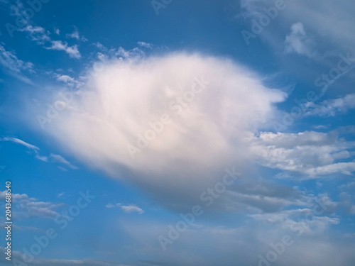 Dramatic cirrus cloud formation with fall streaks, Cirrus virga, over clear blue sky with soft wisps and texture