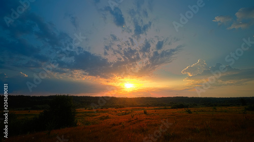 Sunrise over forest with orange and blue sky. Summer landscape.