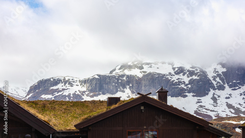 Bild auf Leinwand Remote mountain refuge surrounded by open highland terrain, lingering snowfields and rugged mountain scenery