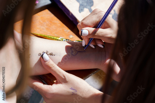 Friends decorating skin with ink at an outdoor fun event during the day