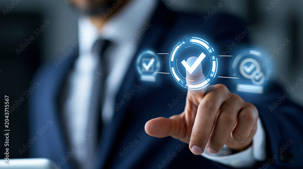 Obraz premium Anonymous businessman in a dark suit touching a holographic compliance screen with glowing checkmarks and regulatory adherence symbols, defocused, with copy space