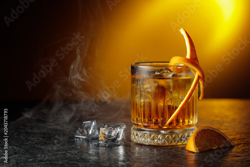 Foto Whiskey with ice in a fogged up glass on a black stone table.