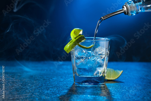 Принти на полотні Vodka with lime and ice cubes in a fogged up glass.